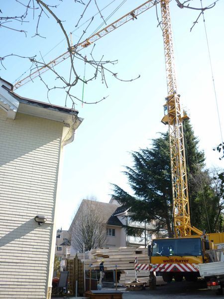 Ein weisser Lkw mit einem gelben Kran darauf. Foto von der Mannhart Holzbau AG