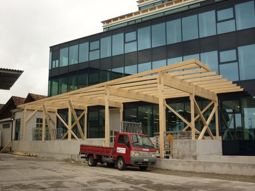 Ein roter Lkw steht vor einem im Bau befindlichen Gebäude. Foto von der Mannhart Holzbau AG