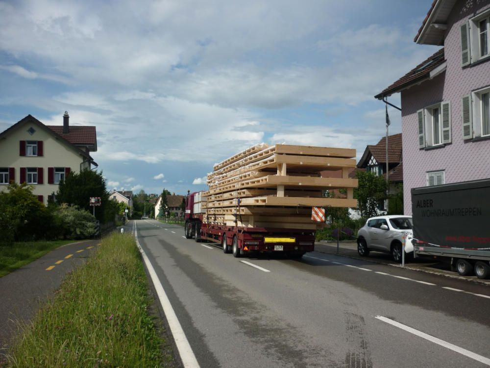 Ein LKW transportiert einen Stapel Holzpaletten eine Straße entlang