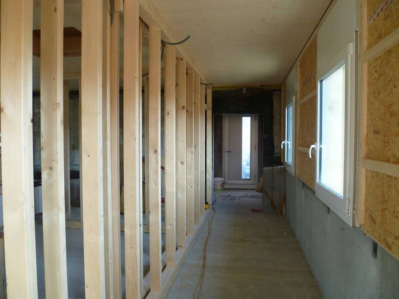 Ein langer Flur mit Holzwänden und Fenstern in einem im Bau befindlichen Haus. Foto von der Mannhart Holzbau AG
