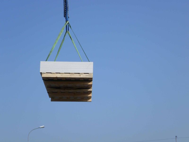 Ein großes Stück Holz wird von einem Kran angehoben