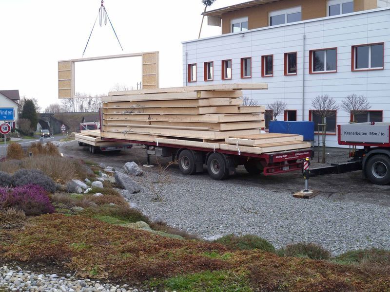 Ein großer Stapel Holz wird von einem Kran auf einen Anhänger gehoben