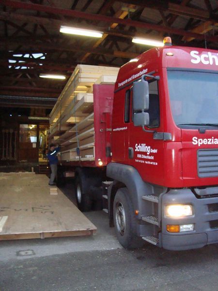 Ein roter Lastwagen transportiert Holz. Foto von der Mannhart Holzbau AG