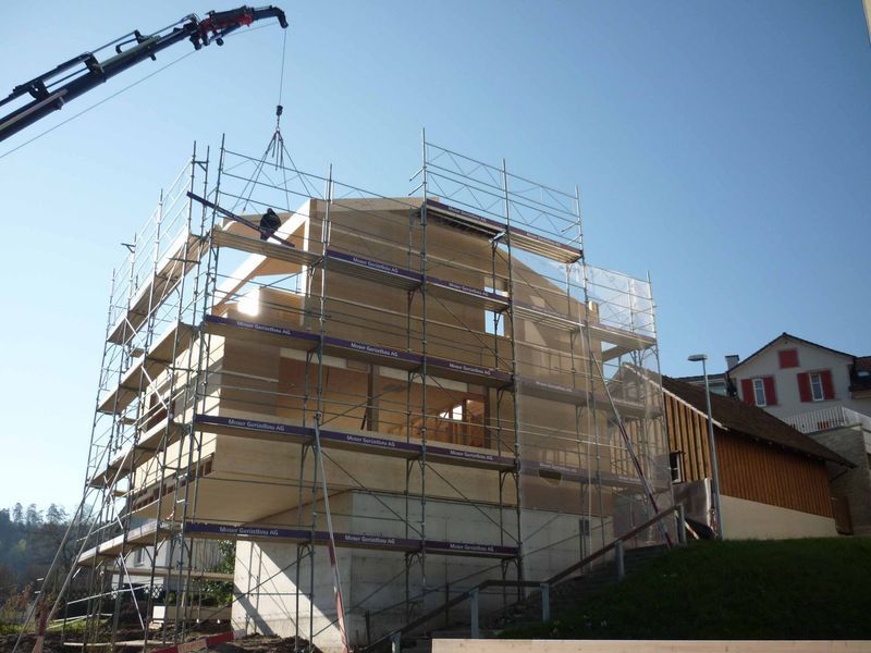 Ein im Bau befindliches Gebäude mit Gerüst und Kran. Foto von der Mannhart Holzbau AG