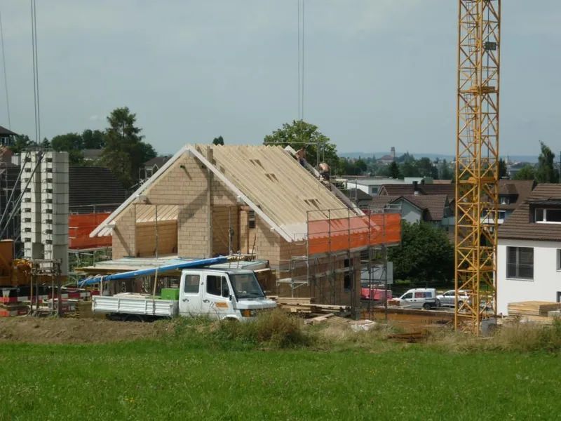 Ein weißer LKW steht vor einem im Bau befindlichen Haus