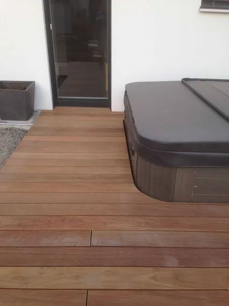 Auf einem Holzdeck steht ein Whirlpool.