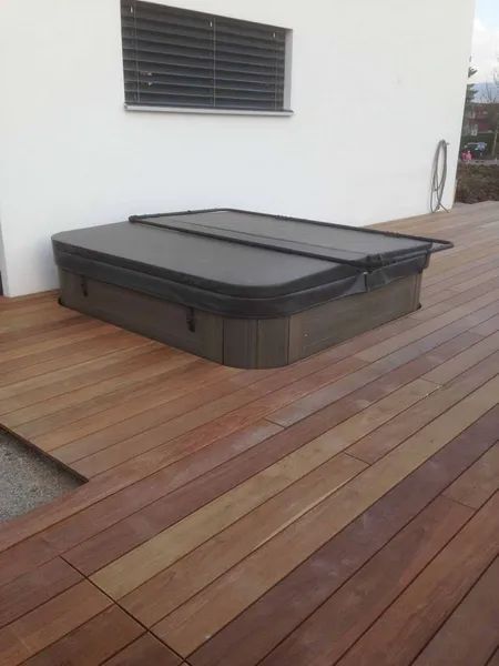 Auf einem Holzdeck steht ein Whirlpool.