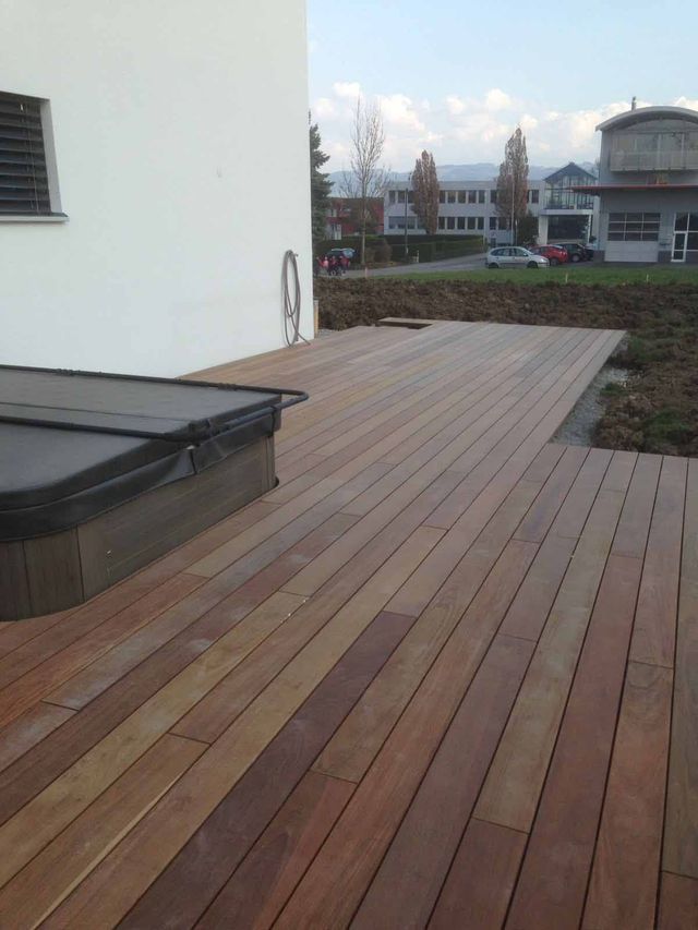 Eine Holzterrasse mit einem Whirlpool darauf. Foto von der Mannhart Holzbau AG