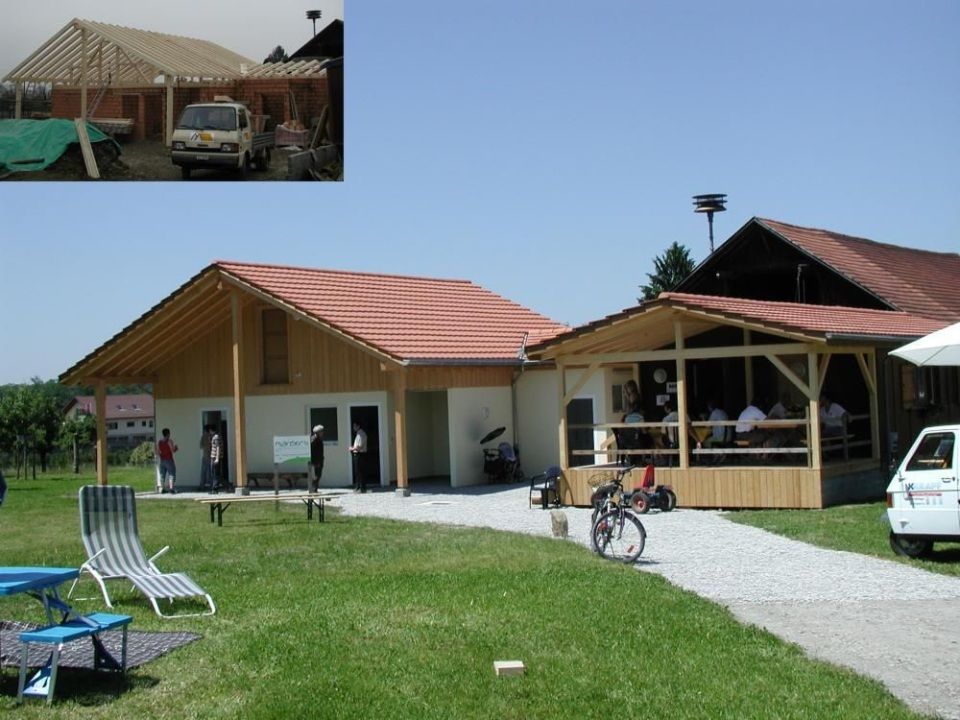 Ein rotes Haus steht auf einem grasbewachsenen Hügel. Foto von der Mannhart Holzbau AG 