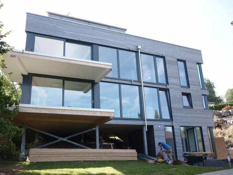 Ein grosses Haus mit vielen Fenstern wird gebaut. Foto von der Mannhart Holzbau AG