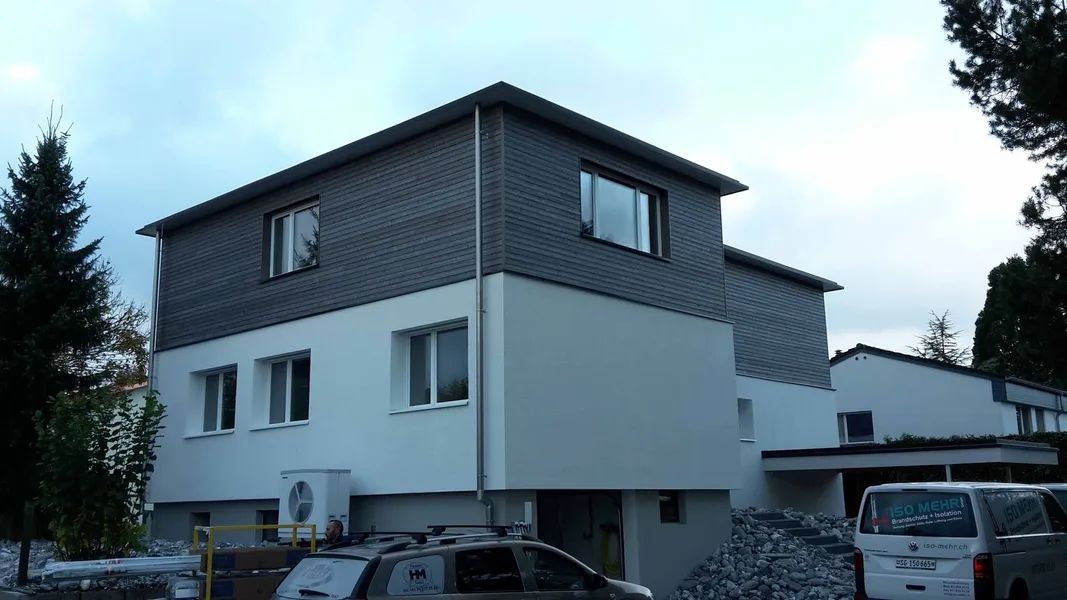 Ein weißes Haus mit einem schwarzen Dach und vielen Fenstern