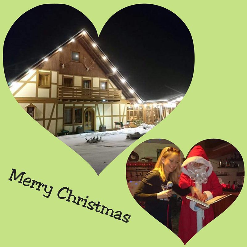 Weihnachtsszene: Beleuchtetes Gebäude, Weihnachtsmann mit einer Frau im Inneren. Schriftzug: „Frohe Weihnachten“.