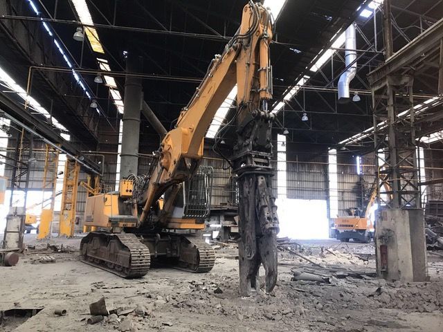 Una gran excavadora amarilla está en un gran almacén.
