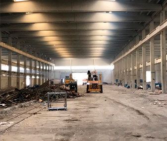 Una excavadora amarilla está destruyendo un edificio en una pila de escombros.