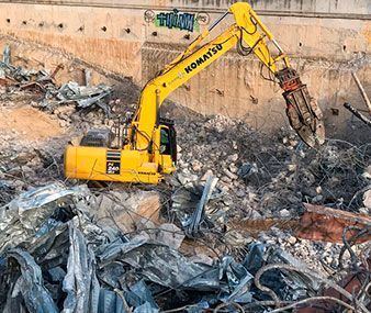 Una excavadora amarilla está destruyendo un edificio en una pila de escombros.