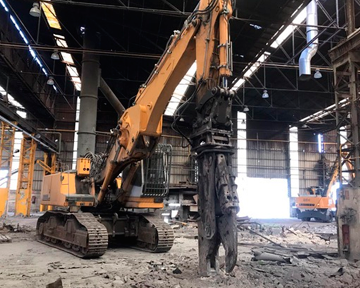 Una gran excavadora está trabajando en un gran almacén.