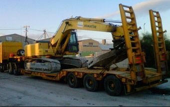 Una excavadora amarilla está encima de un remolque amarillo