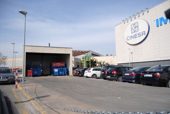 Una fila de autos están estacionados frente a un edificio que dice cinesa