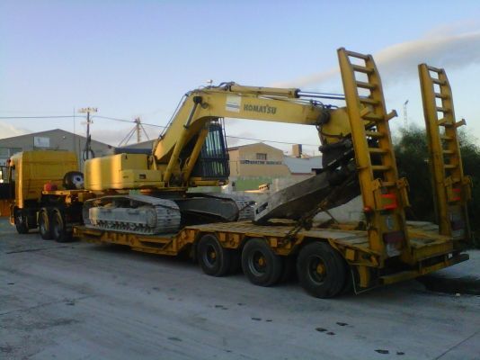 Un camión amarillo con una excavadora Komatsu encima.