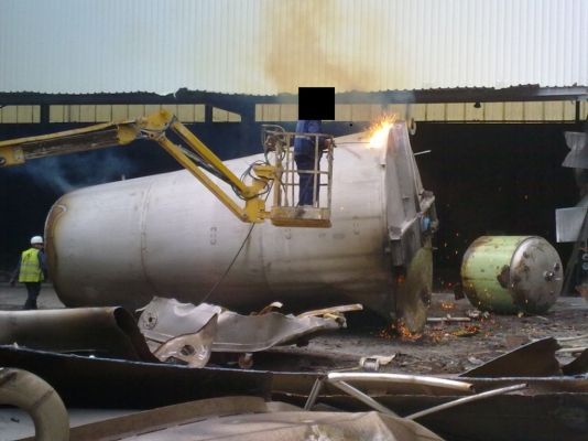 Un hombre está soldando un objeto grande de donde salen chispas.