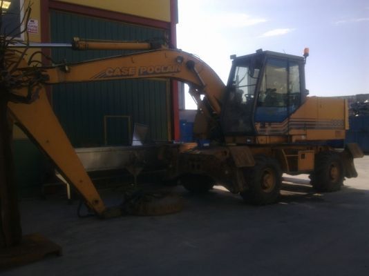 Una excavadora amarilla está estacionada frente a un edificio
