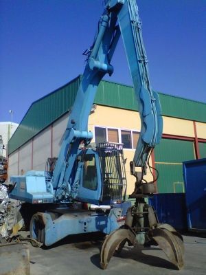 Una gran grúa azul está estacionada frente a un edificio
