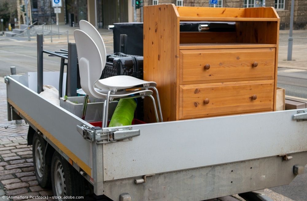 Möbel und Metallgegenstände waren im Laderaum eines kleinen Anhängers auf einer Stadtstraße gestapelt.