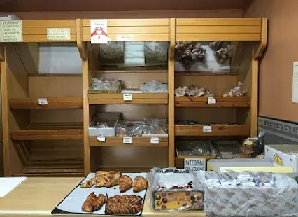 Una panadería con mucho pan en el mostrador y en los estantes.