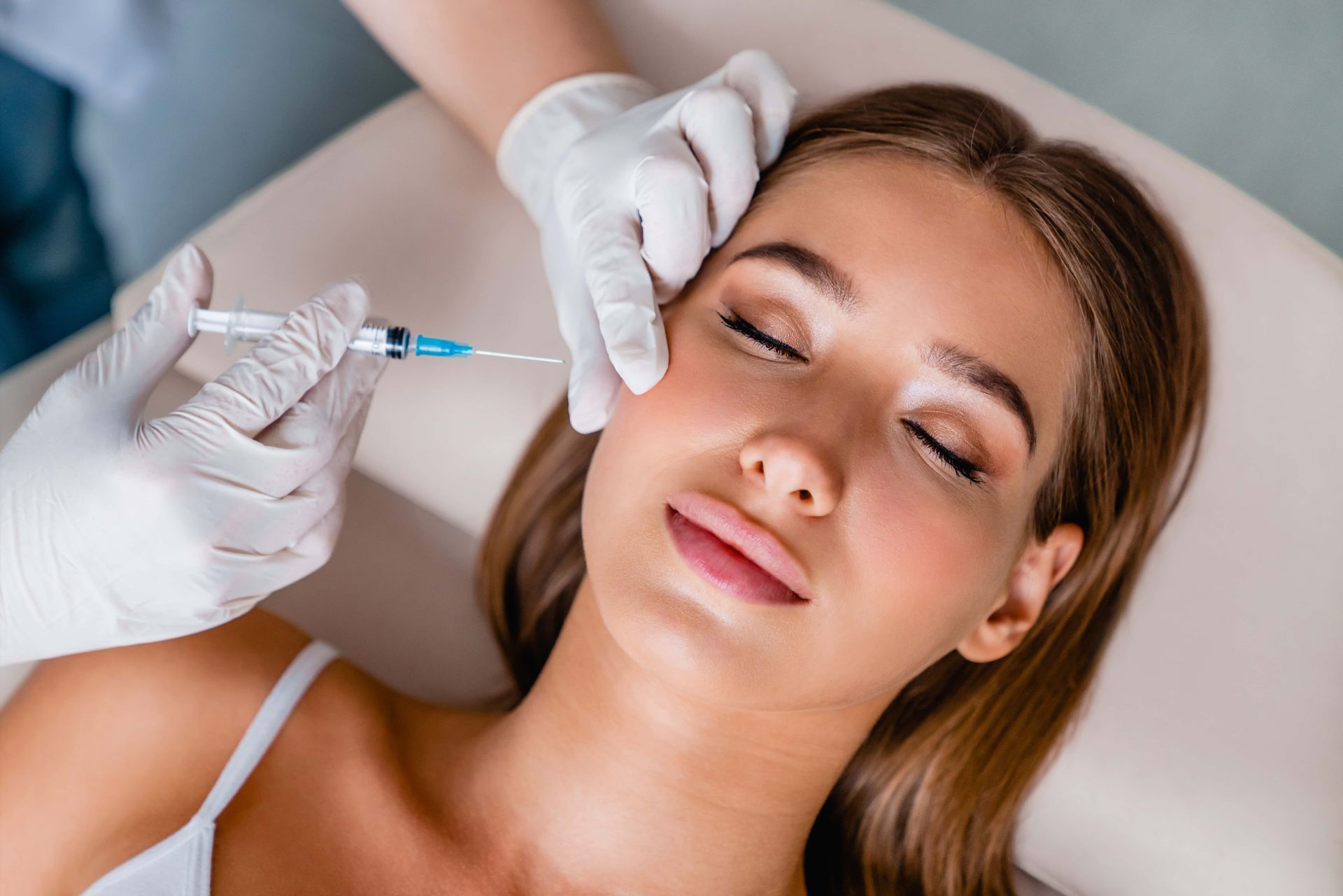 Une esthéticienne administre un traitement par injection faciale à une cliente détendue sur une table de spa