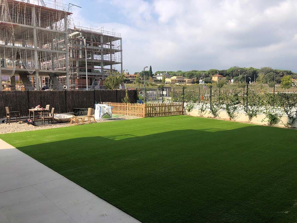 Obra en construcción junto a un césped verde brillante bajo un cielo nublado.