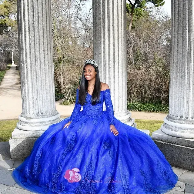 Una mujer con un vestido de baile azul está sentada en un pilar.
