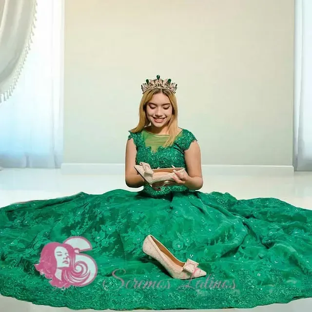 Una mujer con un vestido verde y una corona está sentada en el suelo.