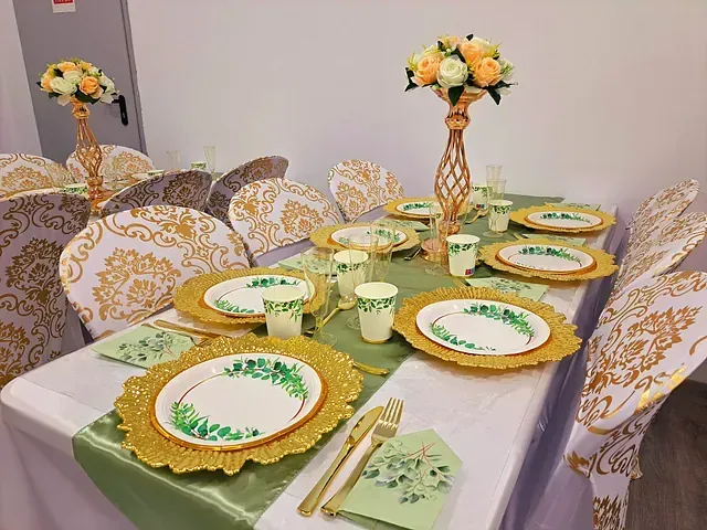 Una mesa con platos, tazas, cubiertos y flores sobre ella.