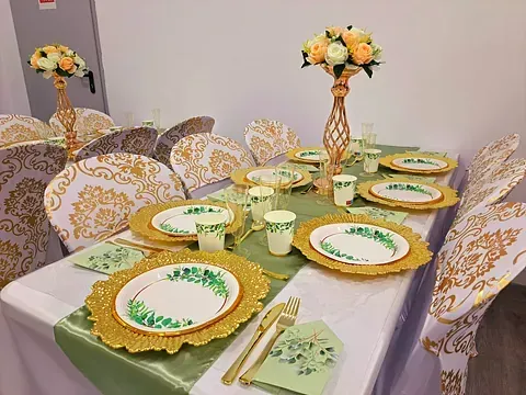 Una mesa preparada para una fiesta con platos, tazas, cubiertos y flores.