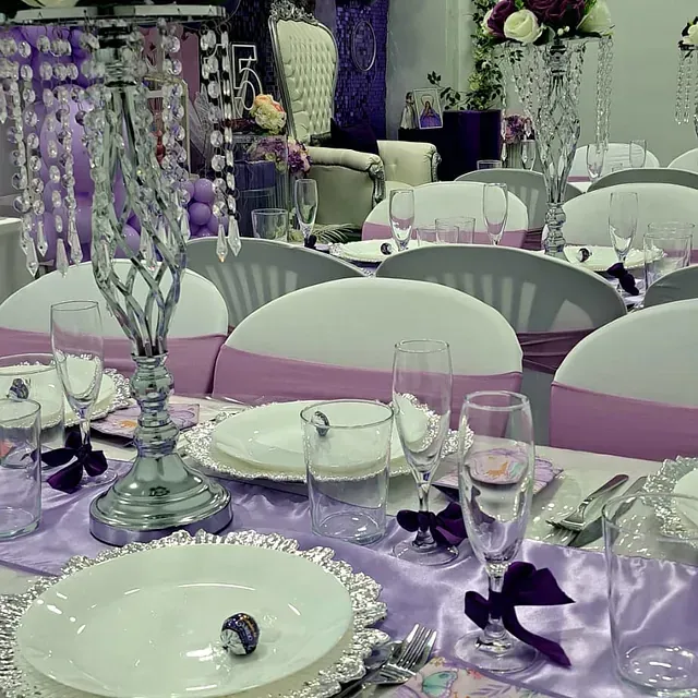 Una mesa preparada para una recepción de boda con platos y vasos.