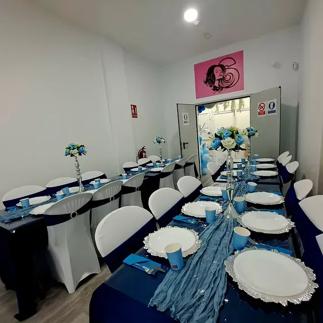 Una sala con mesas y sillas preparadas para una fiesta.