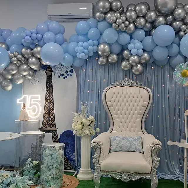 Una habitación decorada con globos azules y plateados y una silla.