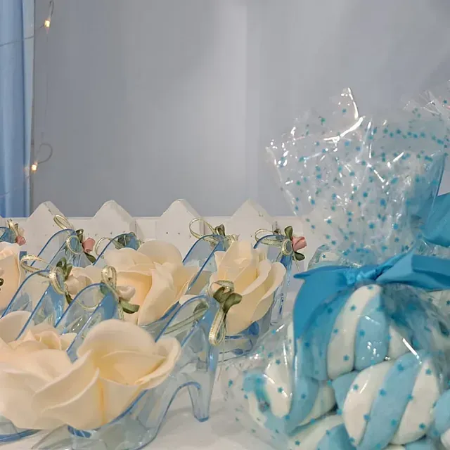 Una bolsa de malvaviscos azules y blancos junto a un ramo de flores.