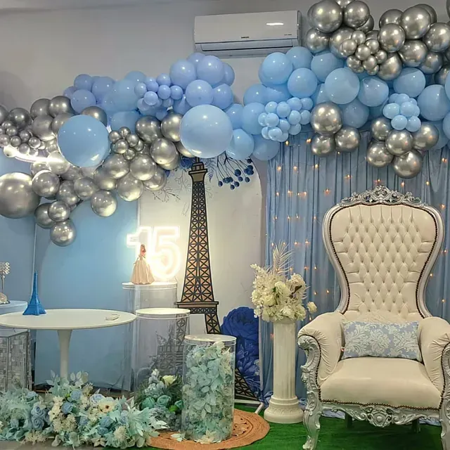 Una habitación decorada con globos azules y plateados y una silla.