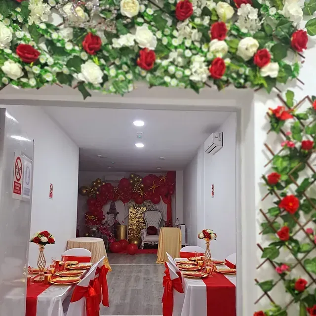 Una habitación decorada con flores rojas y blancas y mesas y sillas.