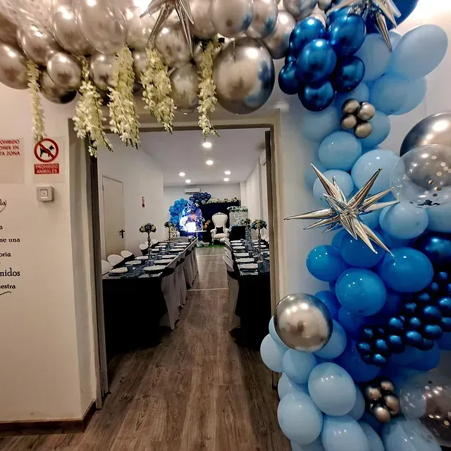 Un pasillo lleno de globos azules y plateados.