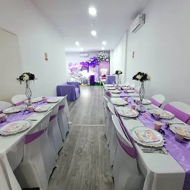 Un largo pasillo con mesas y sillas preparadas para una fiesta.