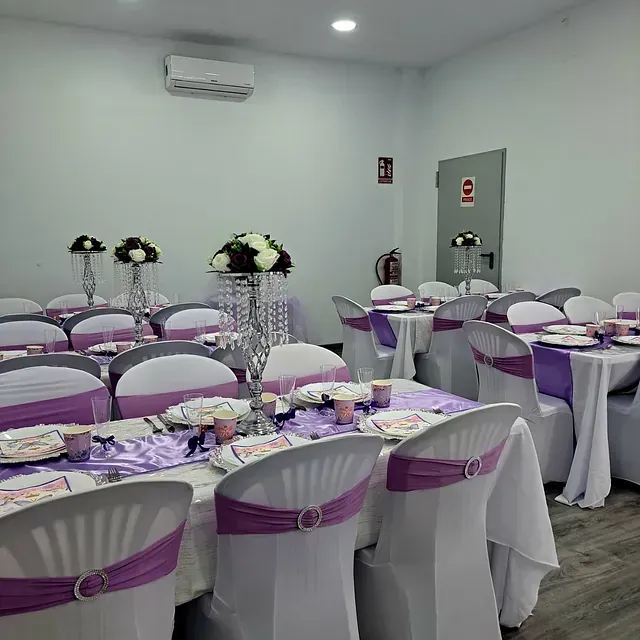 Una sala con mesas y sillas preparadas para una recepción de boda.
