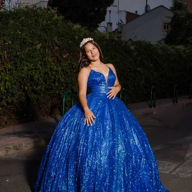 Una mujer lleva un vestido de fiesta azul y una corona.