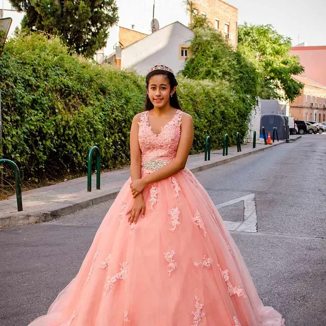 Una mujer con un vestido rosa está parada al costado de la carretera.