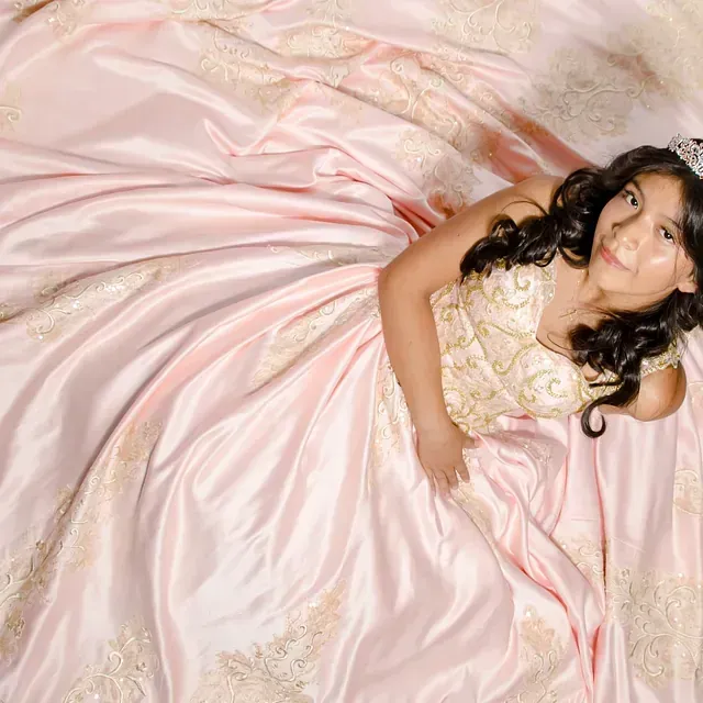 Una niña con un vestido rosa está acostada en una cama.