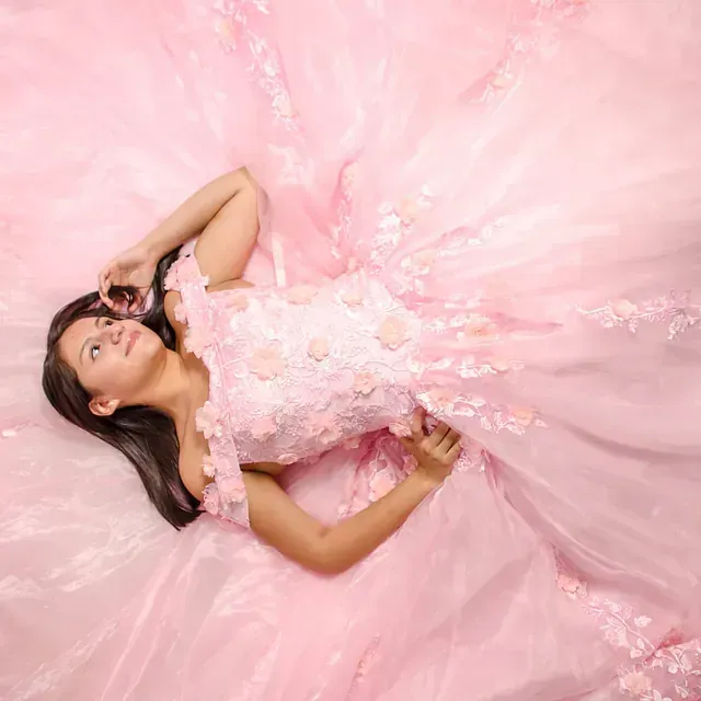 Una mujer con un vestido rosa está tumbada en el suelo.