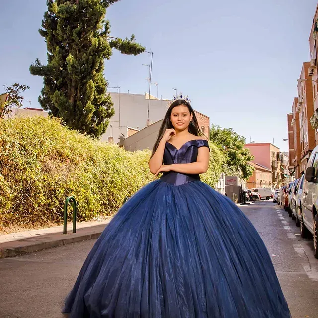 Una mujer con un vestido azul está parada en una calle.