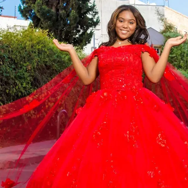 Una mujer con un vestido rojo está de pie con los brazos extendidos.
