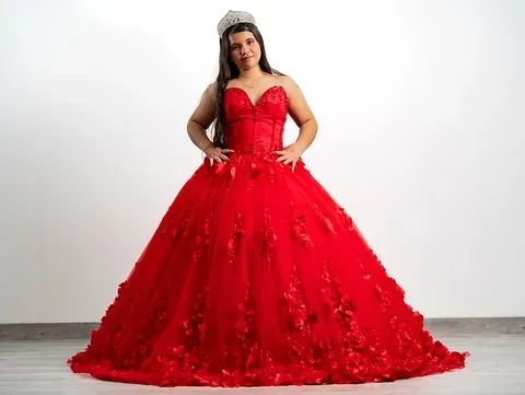 Una mujer lleva un vestido de fiesta rojo y una corona.
